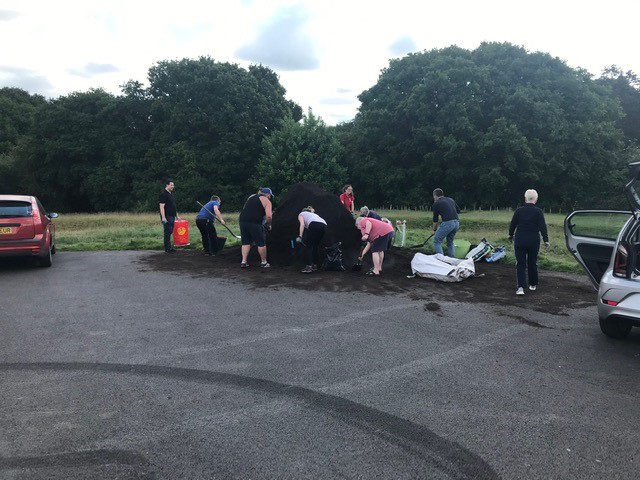 Group of people collecting compost from car park