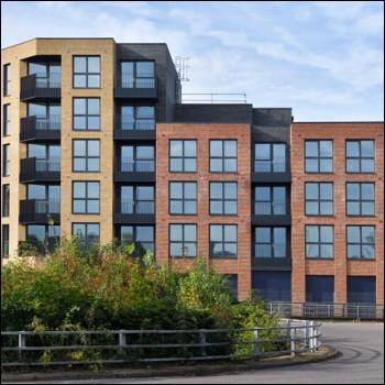 Four and six storey brick apartments with shrubs in front.