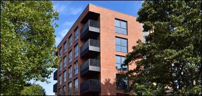 Photo looking up a red brick apartment block with balconies.