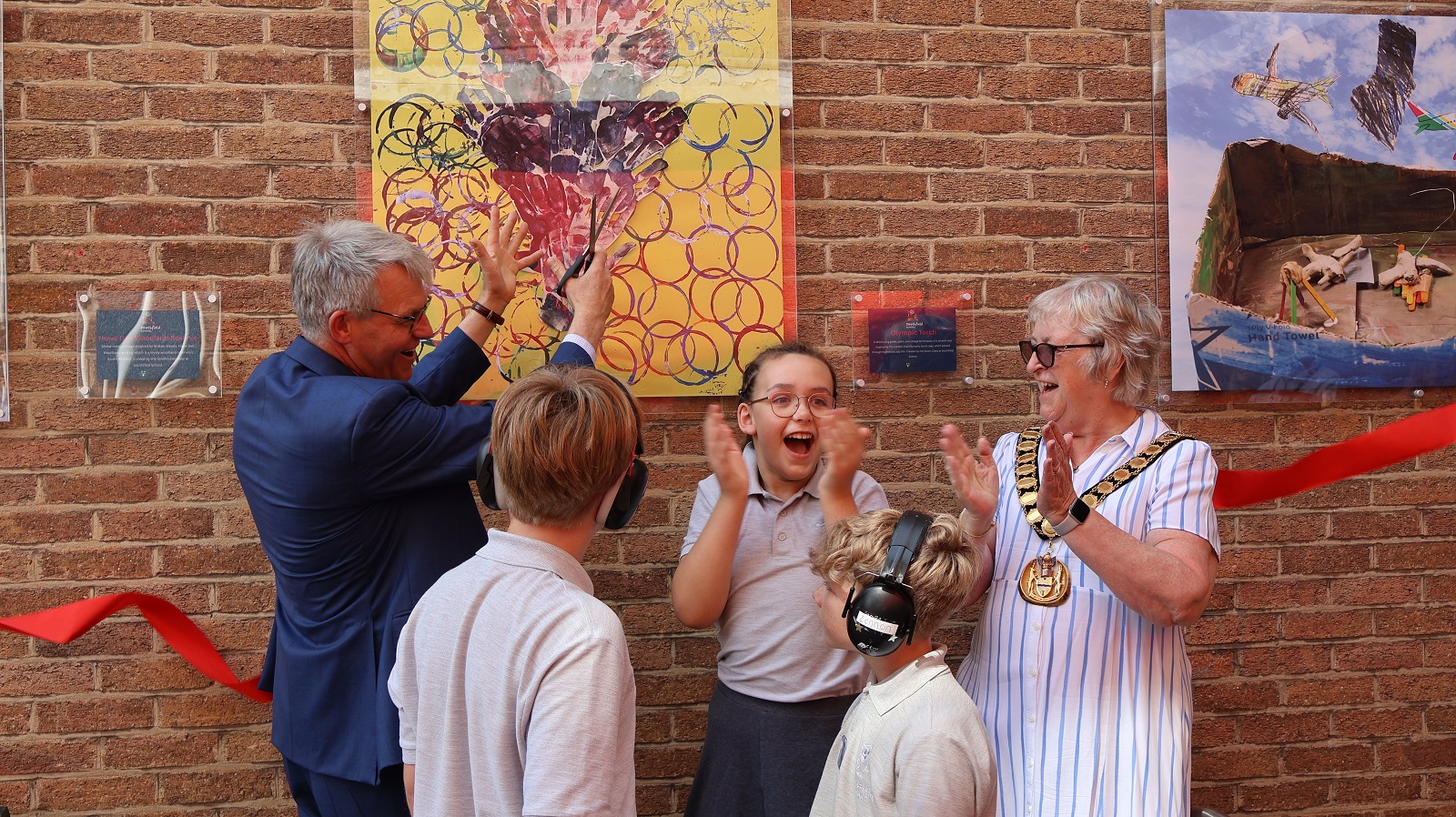 People in front of artwork cutting ribbon