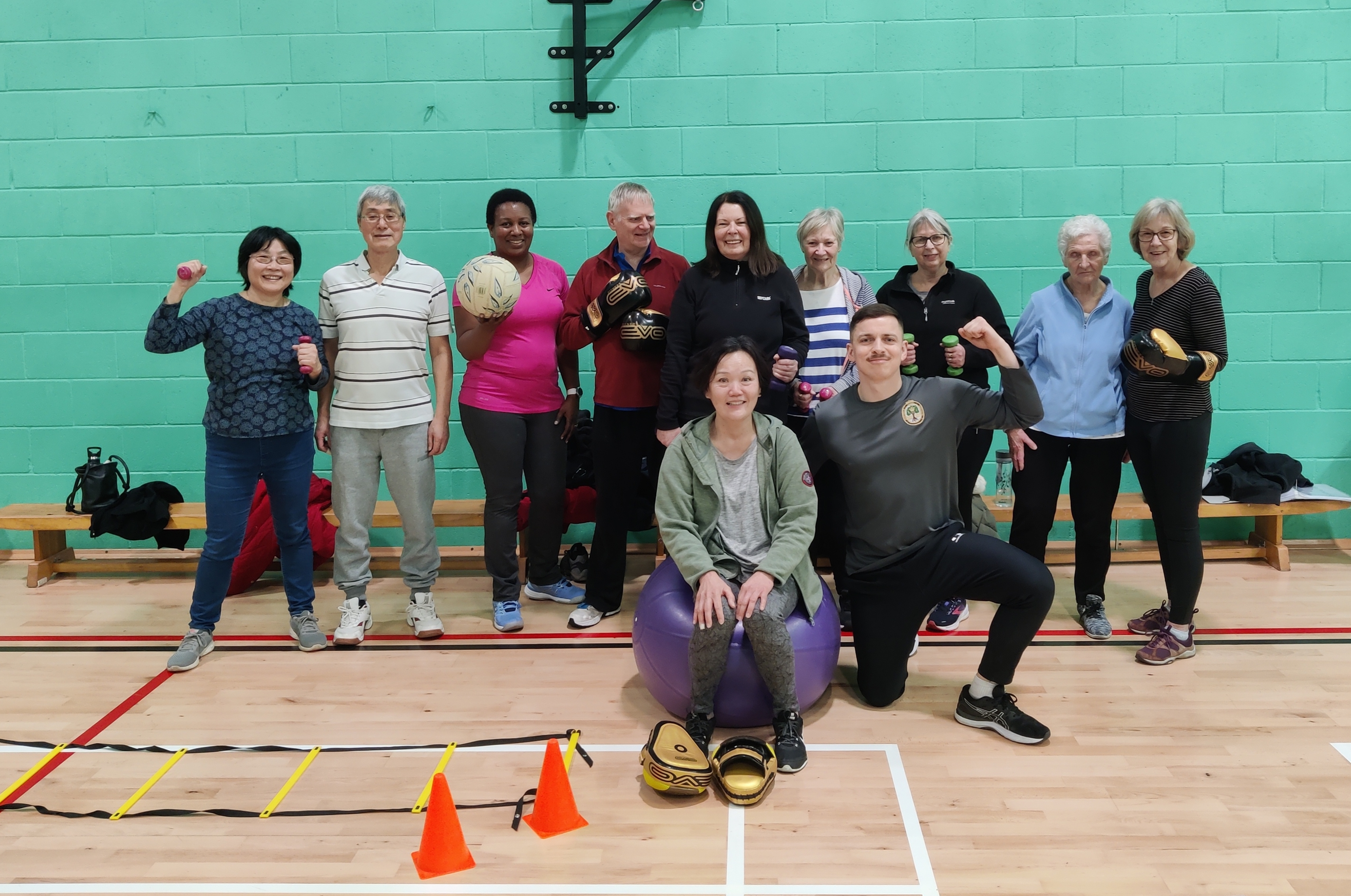 Group of adults in a sports hall holding balls.