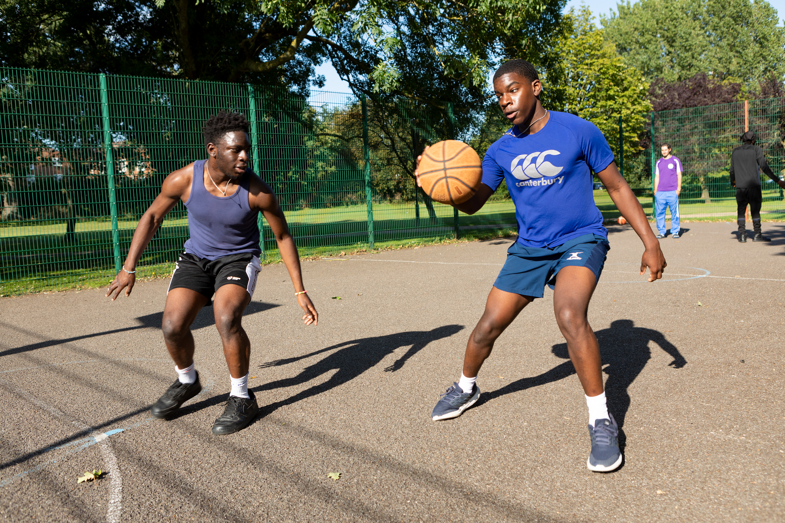 2 Teenagers playing basketball together.