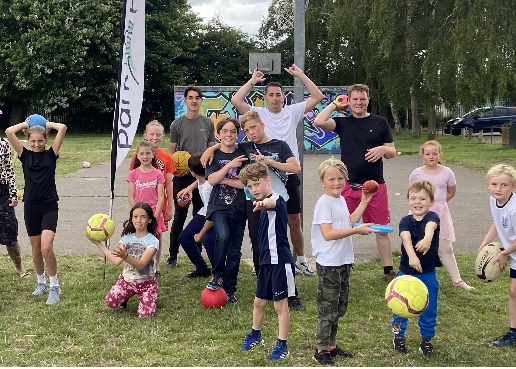 group of children playing in the park with footballs.