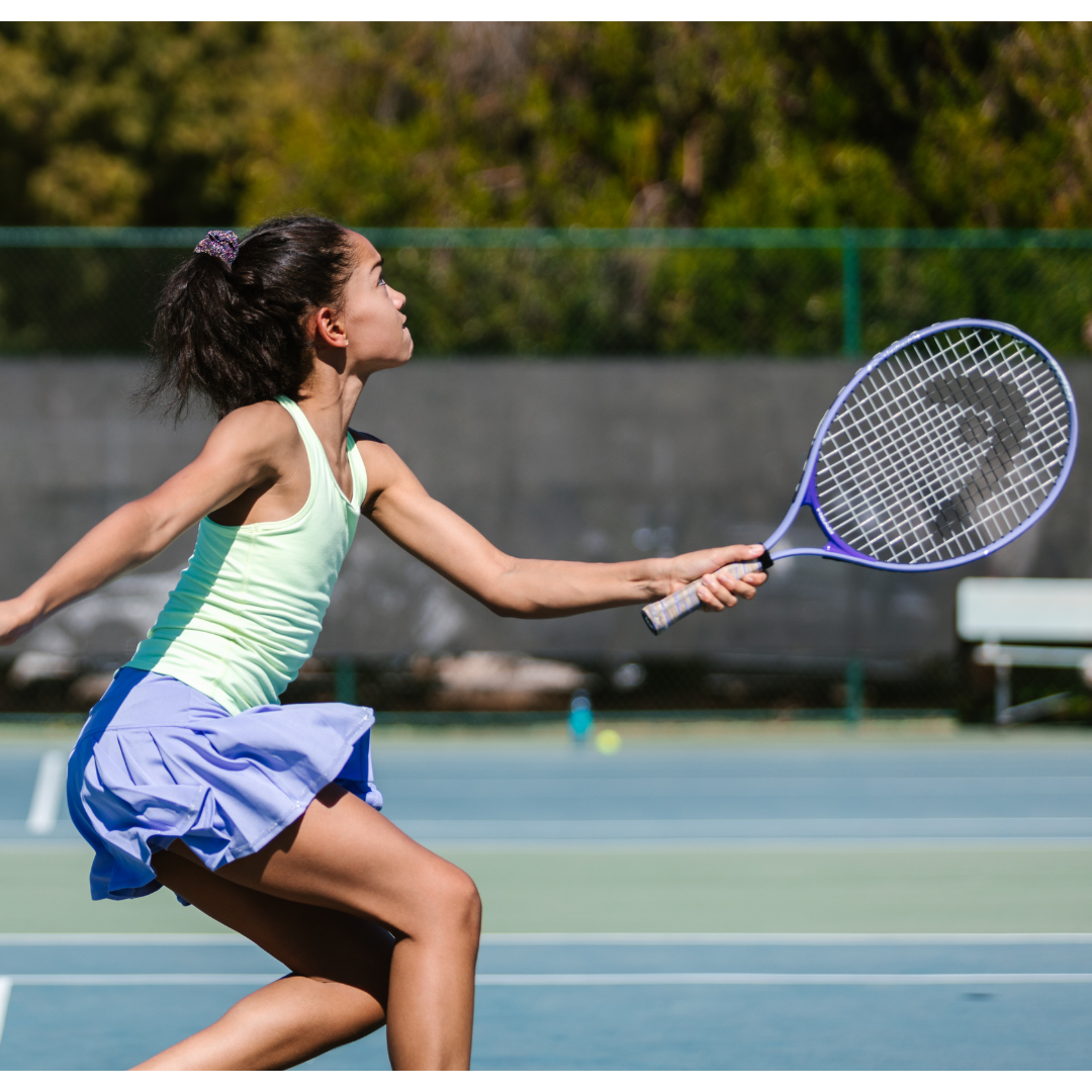 Young girl swinging a tennis racket.