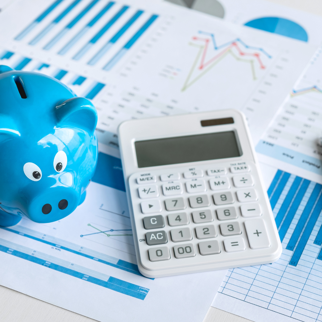 A blue piggy bank and white calculator on top of some finance sheets
