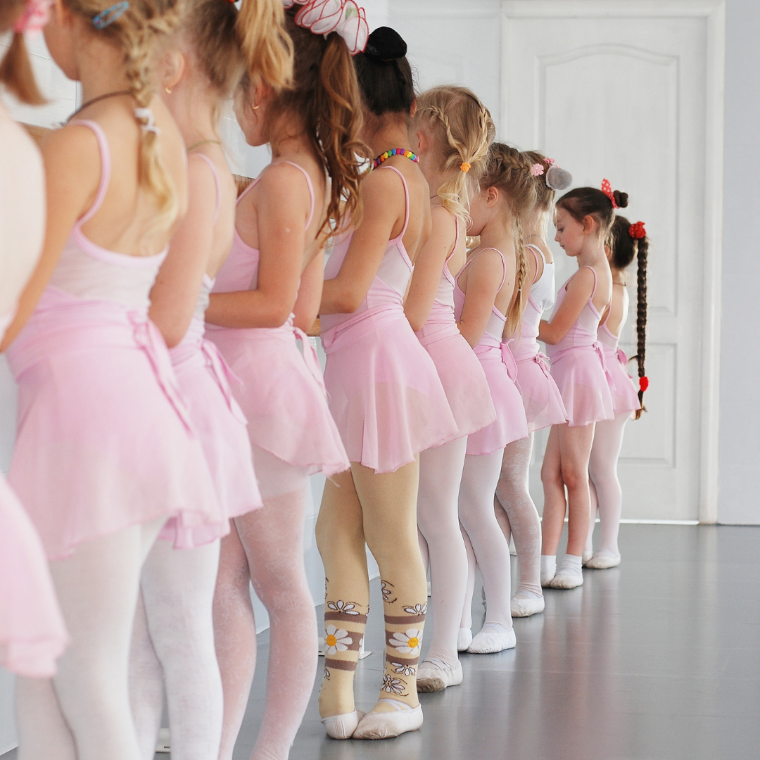 A row of young girls in a ballet class