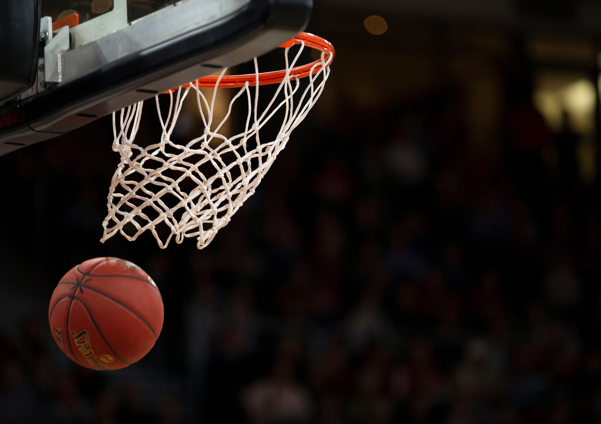 Basketball falling through a basketball net.